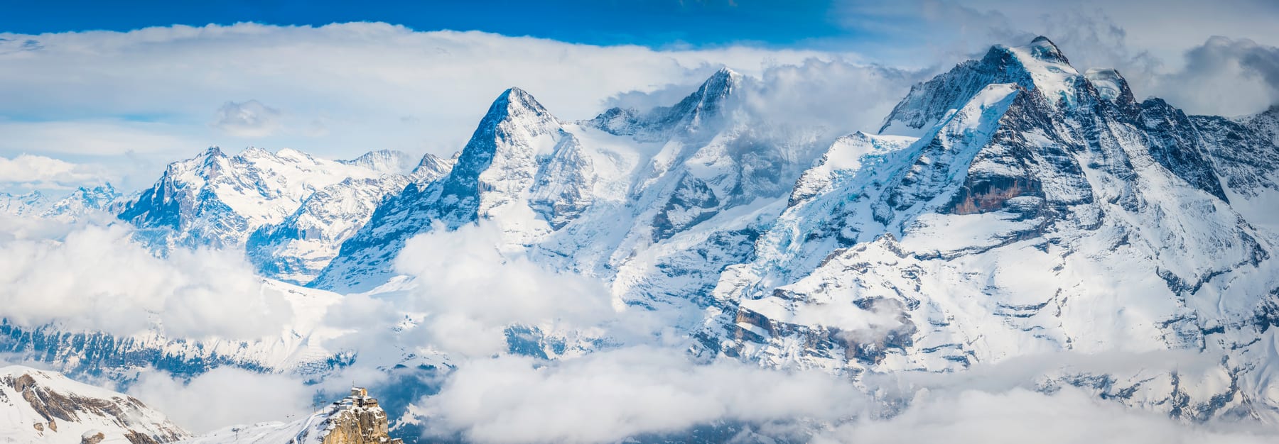 Snowy Eiger, Mönch and Jungfrau peaks amid dramatic cloud above a sea of mist